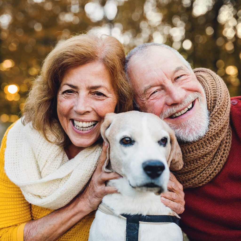 Senior couple with their white labrador dog in nature