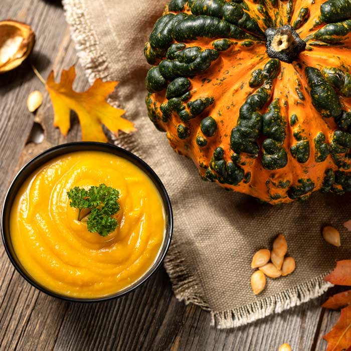 pumkin puree on a wooden table in a bowl a beautiful colorful pumkin next to it