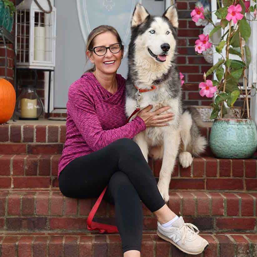 A woman sitting on the porch with a siberian husky
